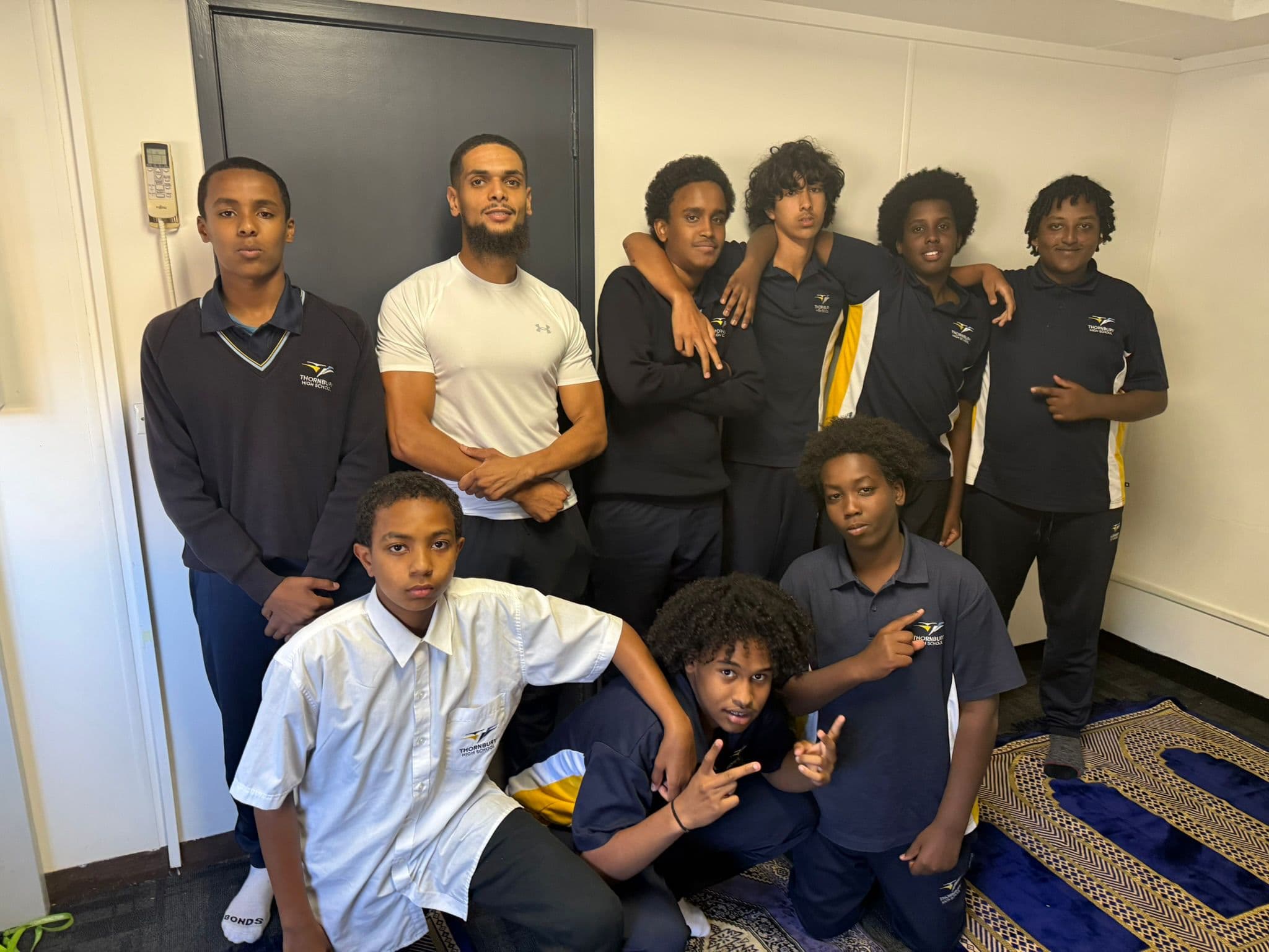 Zayd posing with a group of smiling high school students
