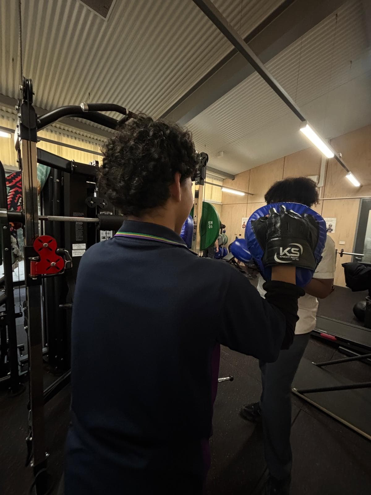 A student doing focus pad boxing work in a gym